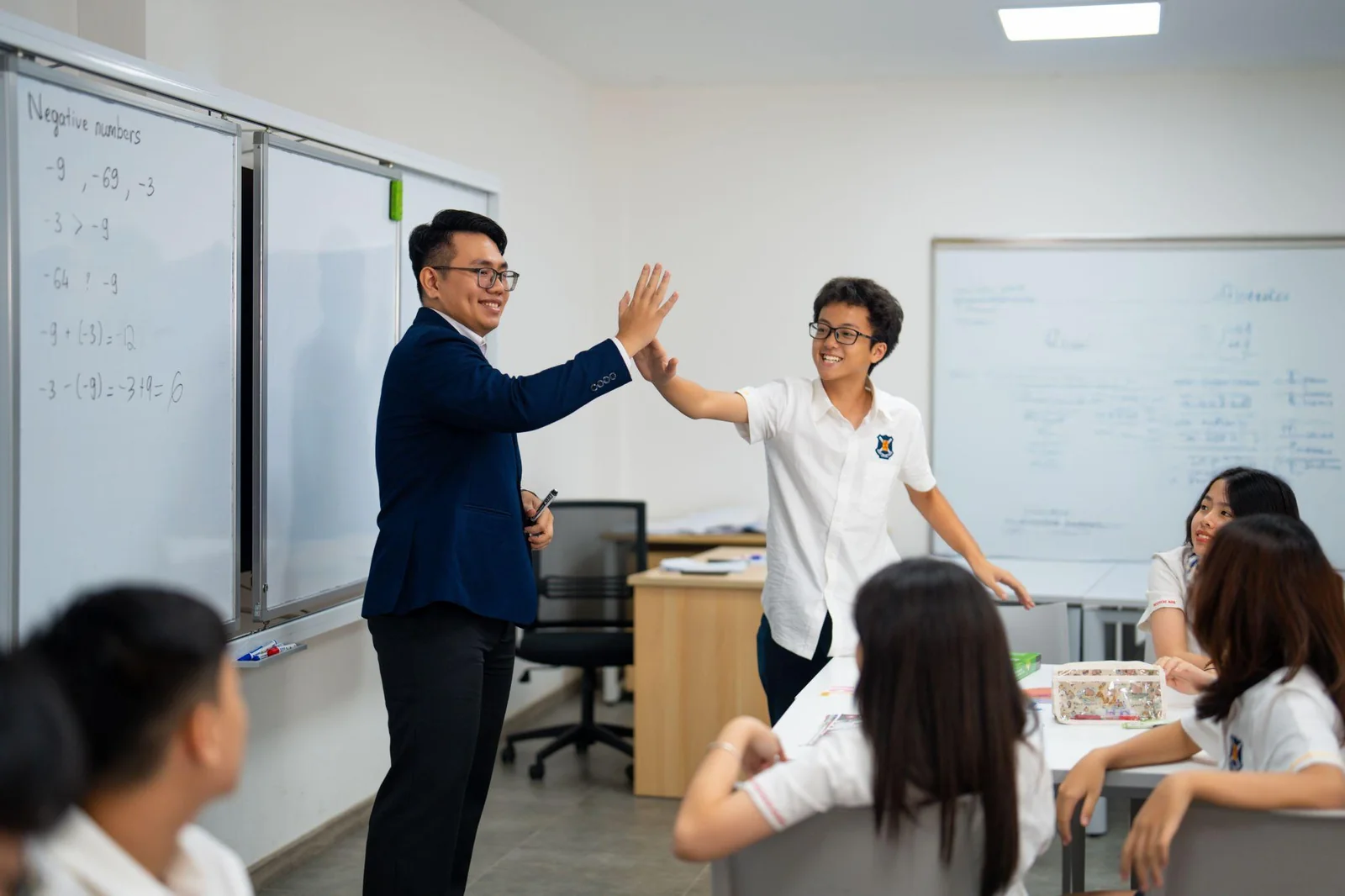 Giáo viên đập tay động viên học sinh trong lớp học, chuẩn bị năng lực học thuật từ sớm