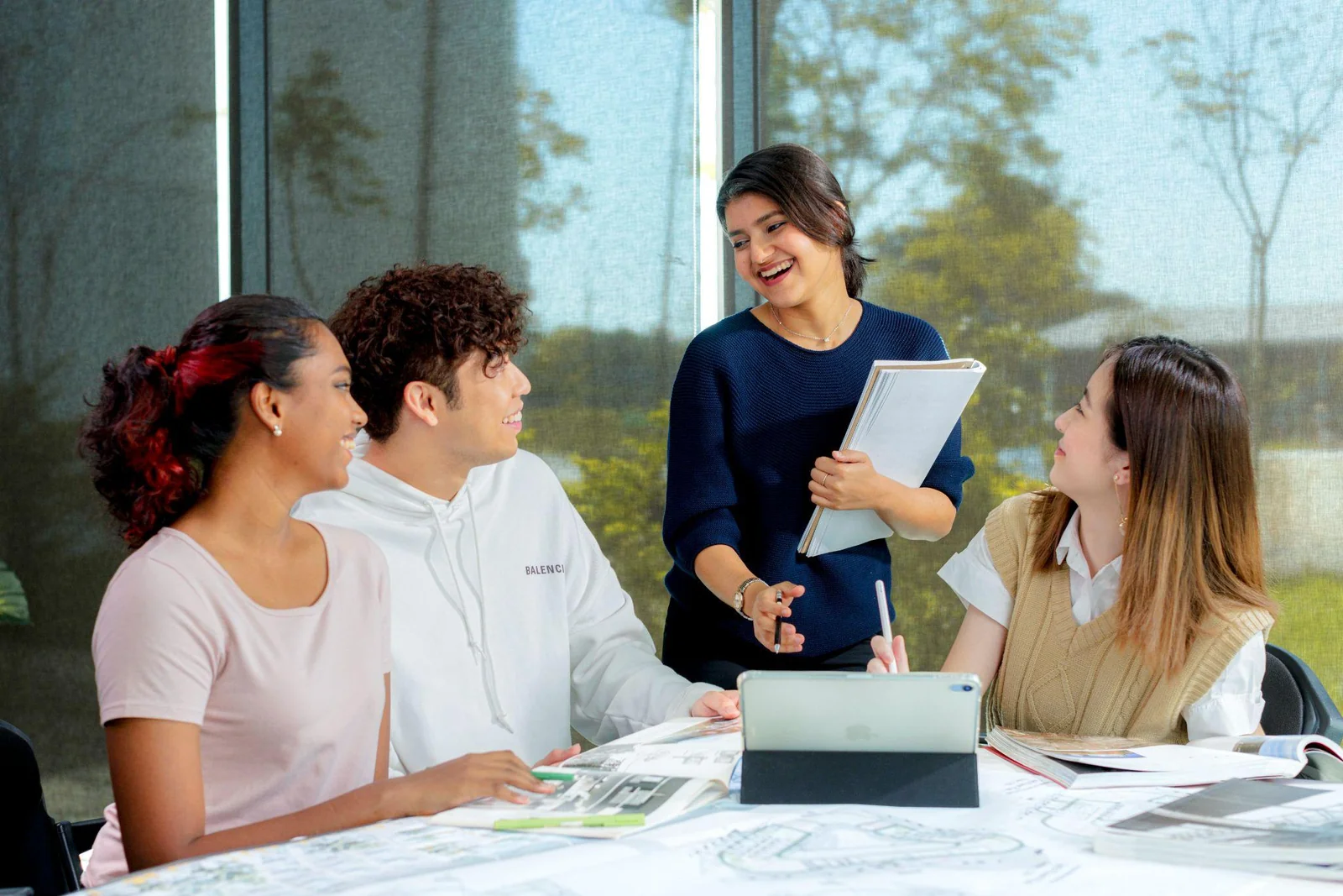 Nhóm sinh viên quốc tế thảo luận và làm việc nhóm quanh bàn học với máy tính bảng