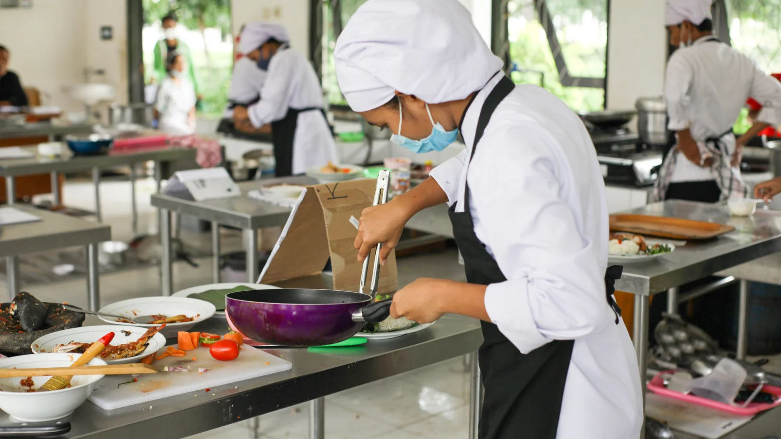 Nhân viên bếp nấu ăn trong căn bếp trường học, hỗ trợ thử bảng chọn khẩu phần